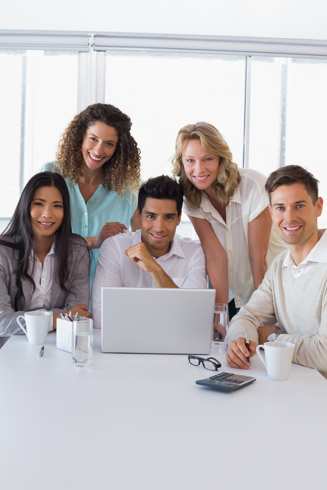 Casual smiling business team having a meeting using laptop in the office